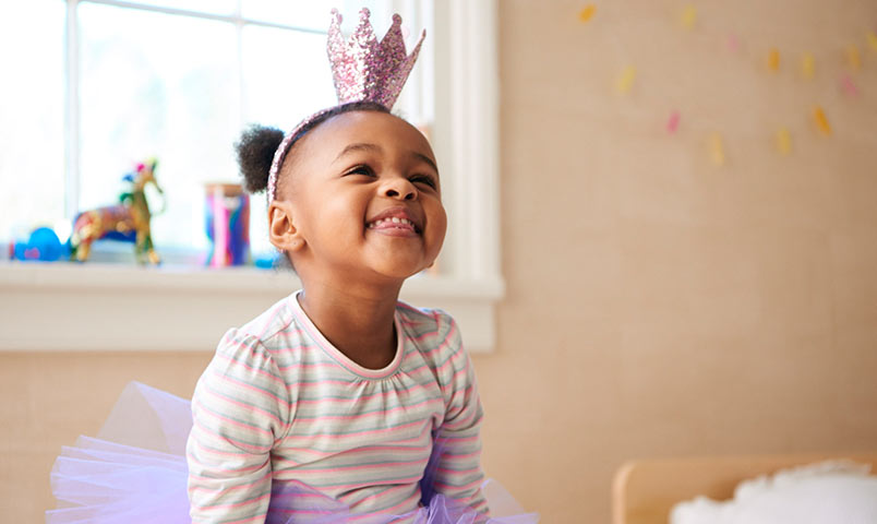 Niña que sonríe con una corona del orinal