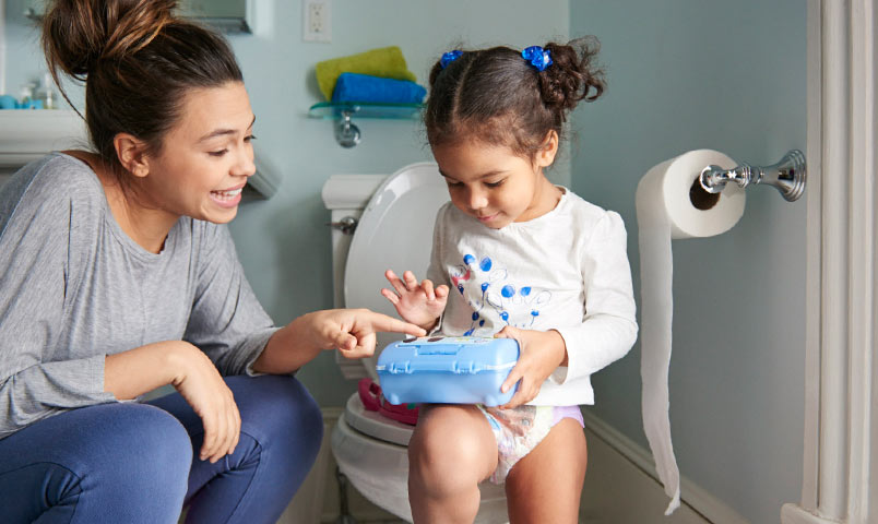 Petite fille assise sur l'apprentissage de la propreté des toilettes avec un parent